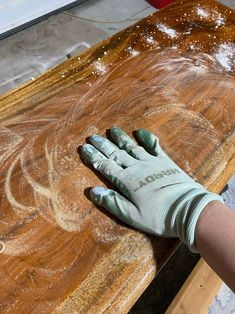 a person with gloves on their hands is sanding down a wooden table and painting it