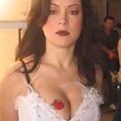 a woman with very large breast wearing a white dress and red lipstick is posing for the camera