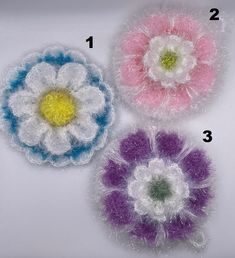 three crocheted flowers are shown on a white surface with the numbers 1, 2, and 3