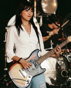 a young woman playing an electric guitar on stage