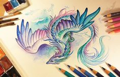 a drawing of a colorful dragon with wings spread out and eyes closed, surrounded by colored pencils