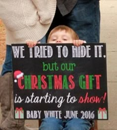 a little boy holding a sign that says, we tried to hide it but our christmas gift is starting to show