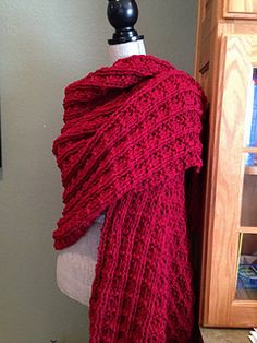 a red knitted shawl draped over a mannequin