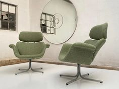 two green chairs sitting next to each other in front of a wall with a mirror on it