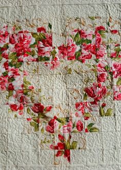 a quilted heart with red flowers on it