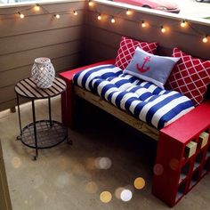 a bed made out of pallet wood with pillows and lights on the wall behind it