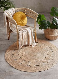 a chair sitting on top of a rug next to a potted plant and a yellow pillow