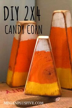 three orange and white striped candy corn vases sitting on top of a wooden table