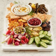 a platter filled with different types of vegetables and crackers on a marble table