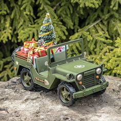 a toy jeep with a christmas tree in the back is on top of a rock