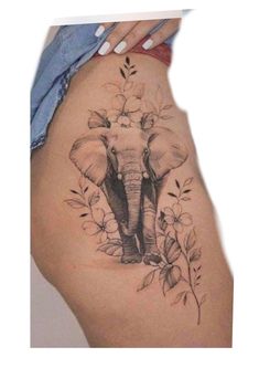 an elephant tattoo on the side of a woman's thigh, with flowers around it