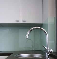 a stainless steel sink and faucet in a kitchen with blue glass backsplash