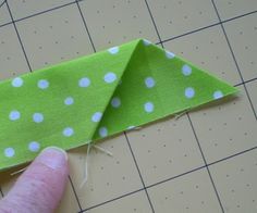 someone is making a green and white polka dot paper origami airplane with one hand