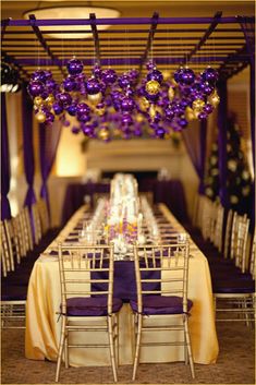 a long table with purple and gold decorations on the top is set up for an event