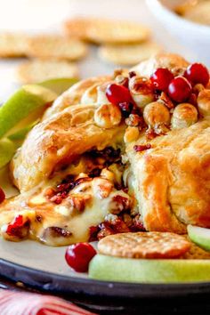 an apple pie is on a plate with crackers and cranberry toppings