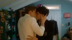 two men are kissing in a room with blue walls