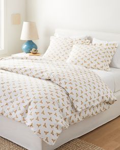 the bed is made with white sheets and gold leaves on it, along with a blue lamp