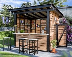 a small outdoor bar with stools and tables in the grass near some flowers, bushes and trees