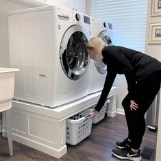 a woman is looking at the front loader of a washer and dryer