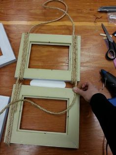 a person is making a frame out of wood and rope on the floor next to scissors