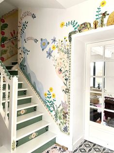 there is a staircase painted with flowers and plants on the wall next to the mirror