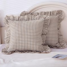 two pillows sitting on top of a bed next to a pillow with ruffled edges