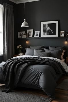 a bedroom with black walls and grey bedding, pictures on the wall above it