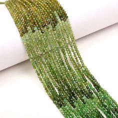 green beaded necklace on white surface next to roll of paper