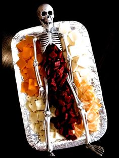 a skeleton is sitting on a platter full of food