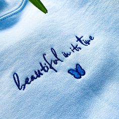 "*SIZES ARE UNISEX* -For women, I'd suggest your usual size for a regular fit (size up for a more relaxed fit). Men should size up for a more relaxed fit. *these sweatshirts are extra comfy when oversized 🦋 \"beautiful in its time\" and a butterfly design embroidered on a comfy light blue crewneck. A sturdy and warm sweatshirt bound to keep you warm in the colder months. A pre-shrunk, classic fit sweater that's made with air-jet spun yarn for a soft feel and reduced pilling. Your new favorite s Casual Embroidered T-shirt For Loungewear, Casual Embroidered Loungewear T-shirt, Custom Embroidery Loungewear Tops, Custom Embroidered Relaxed Fit Tops For Loungewear, Relaxed Fit Tops With Custom Embroidery For Loungewear, Blue Embroidered Text Sweatshirt With Relaxed Fit, Blue Tops With Embroidered Logo For Spring, Blue Tops With Embroidered Text And Relaxed Fit, Blue Relaxed Fit Top With Embroidered Text