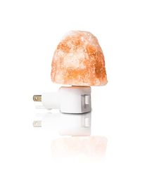 an orange and white mushroom shaped object is plugged into a charger on a white surface