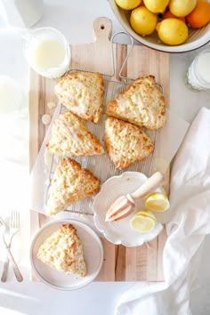 lemon scones are sitting on a cutting board next to bowls of lemons and milk