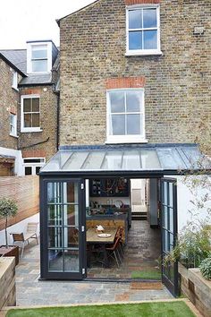 an outdoor dining area in front of a brick building with a glass roof and sliding doors