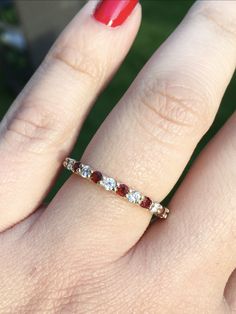 a woman's hand with a red and white diamond ring on her left finger