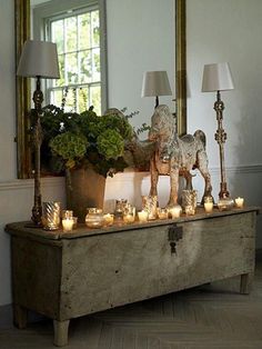 a table with candles and a horse figurine on it in front of a mirror