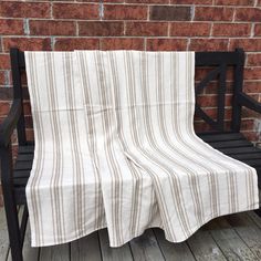 a black bench sitting next to a brick wall with a striped blanket on top of it