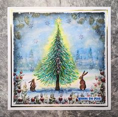 a christmas card with an image of a tree in the snow and rabbits around it