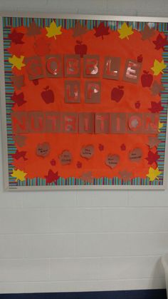 an orange bulletin board hanging on the wall in a room with blue and white flooring