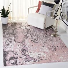 a white chair sitting in front of a window next to a pink rug on top of a floor