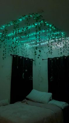 a bed with green lights hanging from the ceiling and curtains on the wall above it