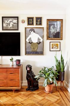 a living room with pictures on the wall and a dog statue in front of it