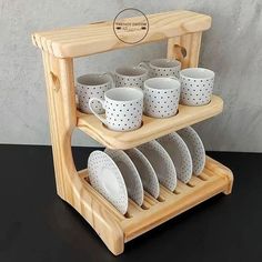 a wooden rack with cups and saucers on it, sitting on a black table