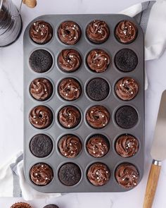 cupcakes with chocolate frosting and sprinkles in a muffin tin