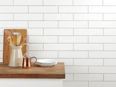 a wooden cutting board sitting on top of a counter next to a white tiled wall