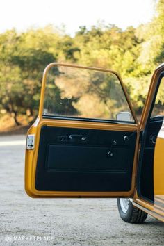 an old yellow car with its door open and it's side window partially closed