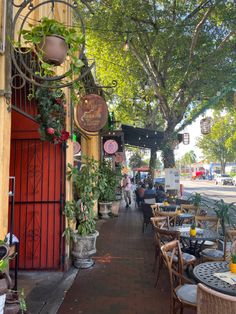 an outdoor restaurant with tables and chairs on the side walk next to a red door