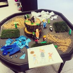 a black table topped with lots of toys and paper on top of it next to a book