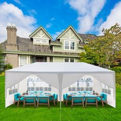 a large tent set up in the grass with blue cushions and chairs under it on a sunny day