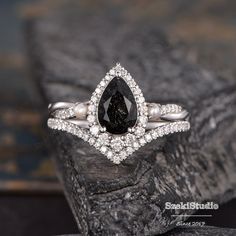 a black and white diamond ring on top of a rock with diamonds around the band