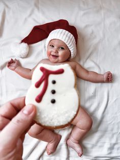 a baby wearing a santa hat and holding a cookie